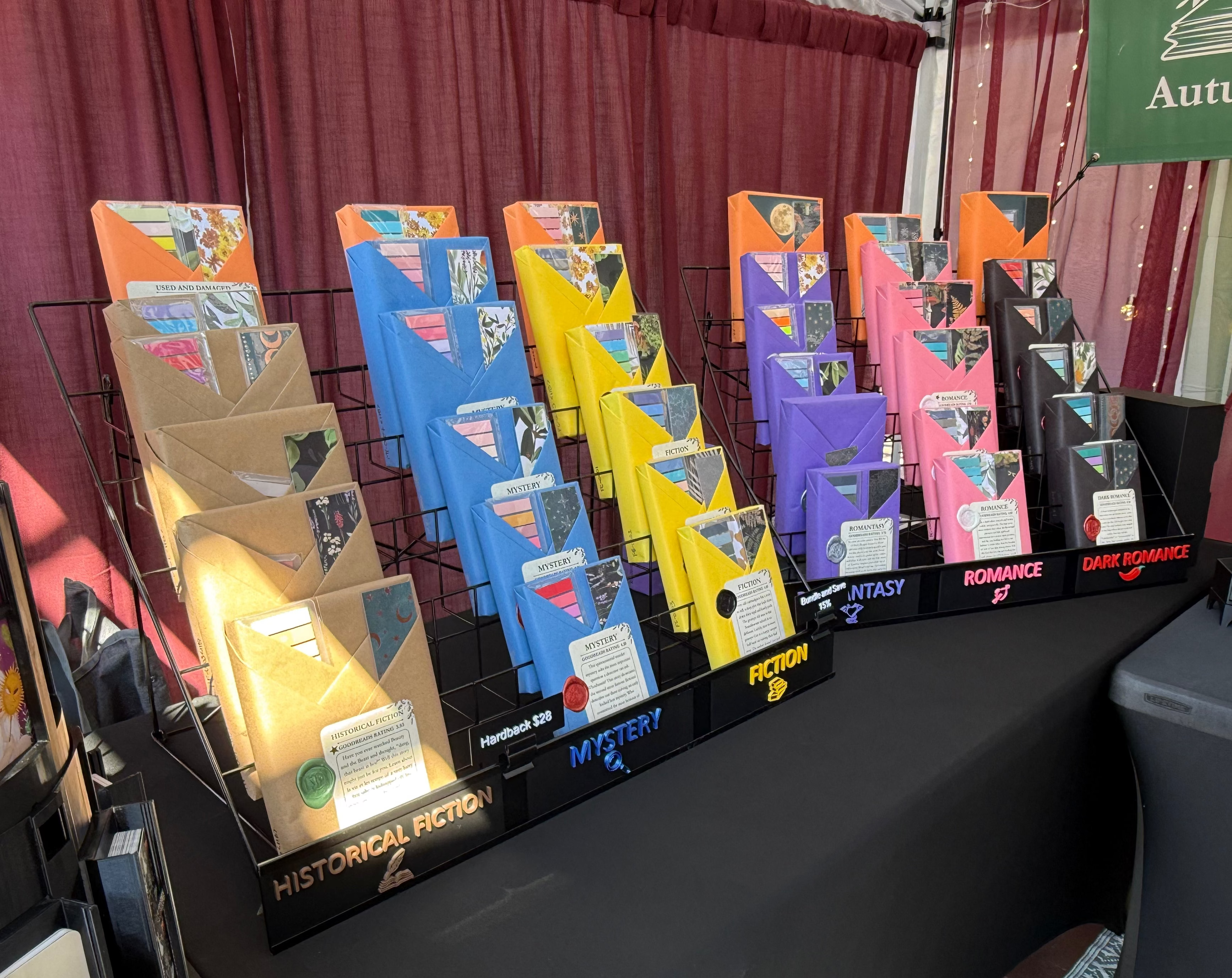 Display of book jackets on a table with a burgundy curtain background